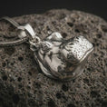 Load image into Gallery viewer, Polished silver hippo head pendant necklace on textured volcanic rock, centered macro jewelry photo with detailed animal charm sculpting and bright silver highlights.
