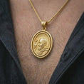 Load image into Gallery viewer, Gold plated Saint Padre Pio spinning pendant necklace worn on the neck, captured in a premium lifestyle composition that highlights the rotating saint medal as a spiritual Christian statement piece.
