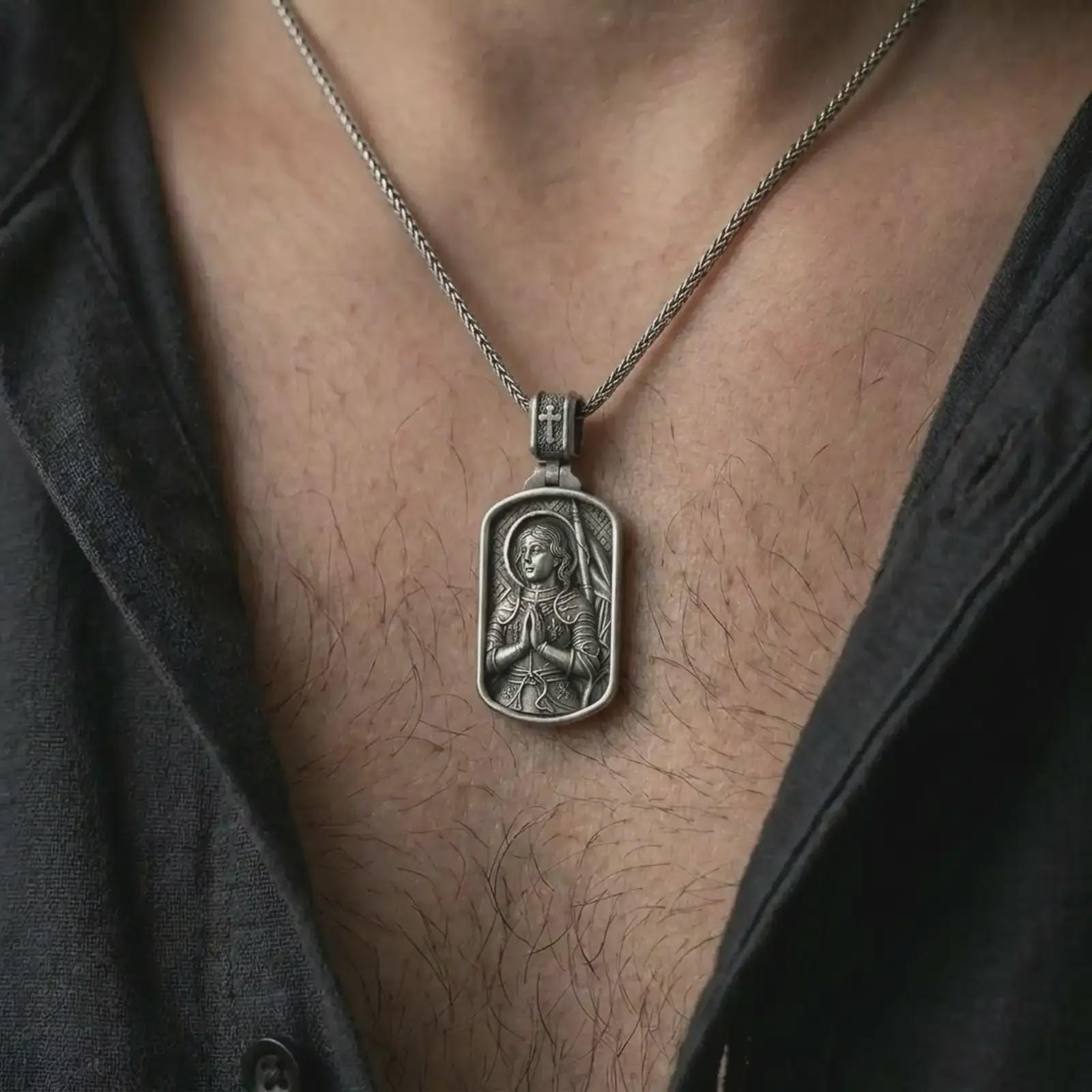 Oxidized Joan of Arc dog tag pendant necklace worn on the neck, styled in a dark lifestyle image that presents the saint warrior medal as a symbol of faith, courage, and spiritual strength.
