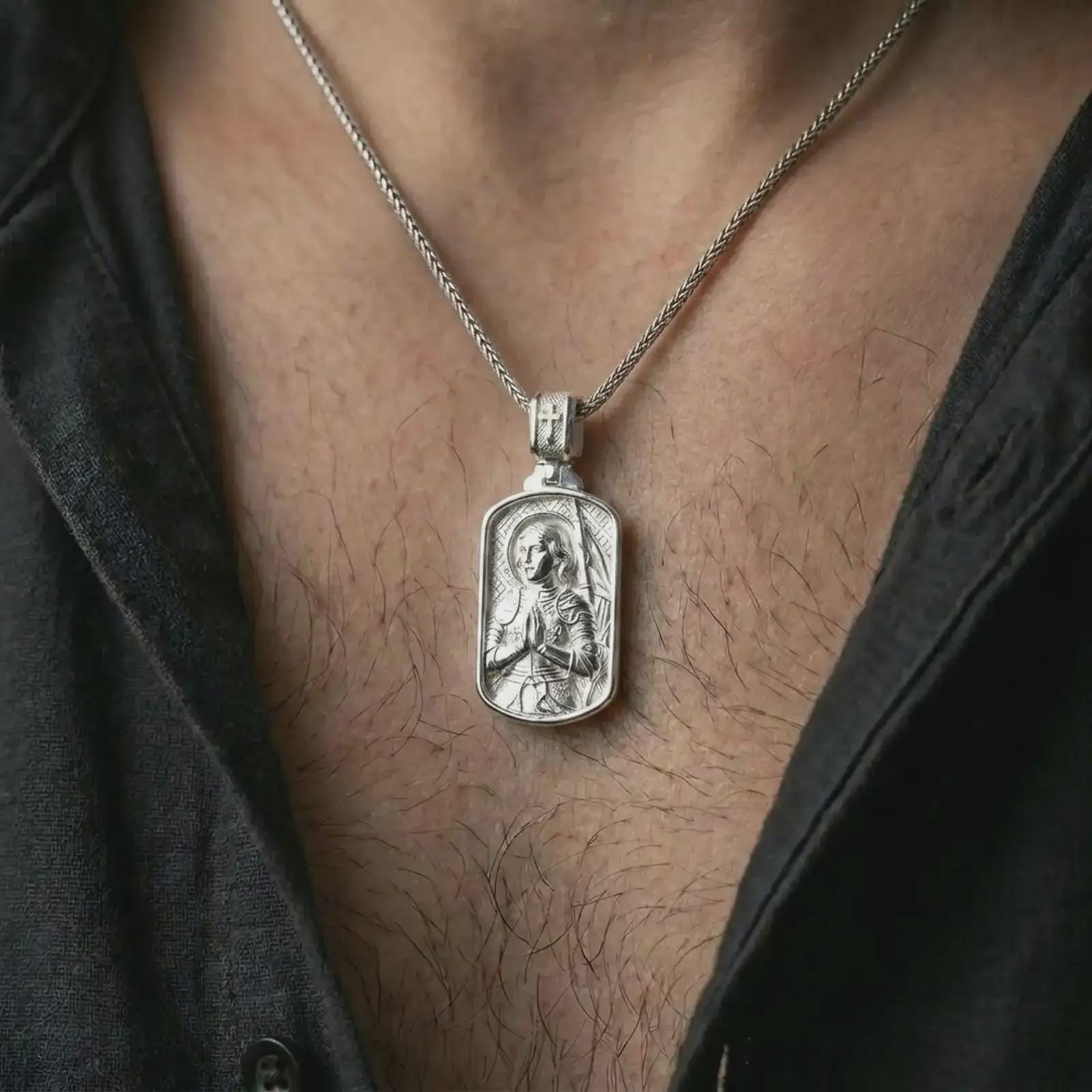 Polished silver Joan of Arc dog tag pendant necklace worn on the neck, shown in a clean model shot with the detailed saint portrait centered for a timeless devotional look.