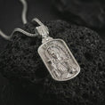 Load image into Gallery viewer, Polished silver Saint Barbara pendant necklace on textured volcanic rock, centered macro jewelry photo with detailed religious icon engraving and bright silver highlights.
