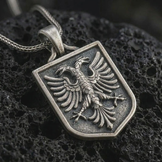 Oxidized Bundesadler pendant necklace on textured volcanic rock, close-up studio shot highlighting the German federal eagle relief, shield frame, spread wings, and antique silver contrast.