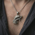 Load image into Gallery viewer, Oxidized chameleon pendant necklace worn on the chest, close-up lifestyle jewelry photo showing the reptile charm on a spiga chain with dark clothing.
