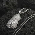 Load image into Gallery viewer, Polished silver feather headdress chief pendant necklace on textured volcanic rock, centered macro jewelry photo with detailed portrait relief and bright silver highlights.
