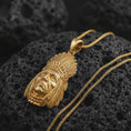 Load image into Gallery viewer, Gold plated feather headdress chief pendant necklace on textured volcanic rock, premium close-up studio composition emphasizing the feather crown, expressive face, and tribal-inspired design.
