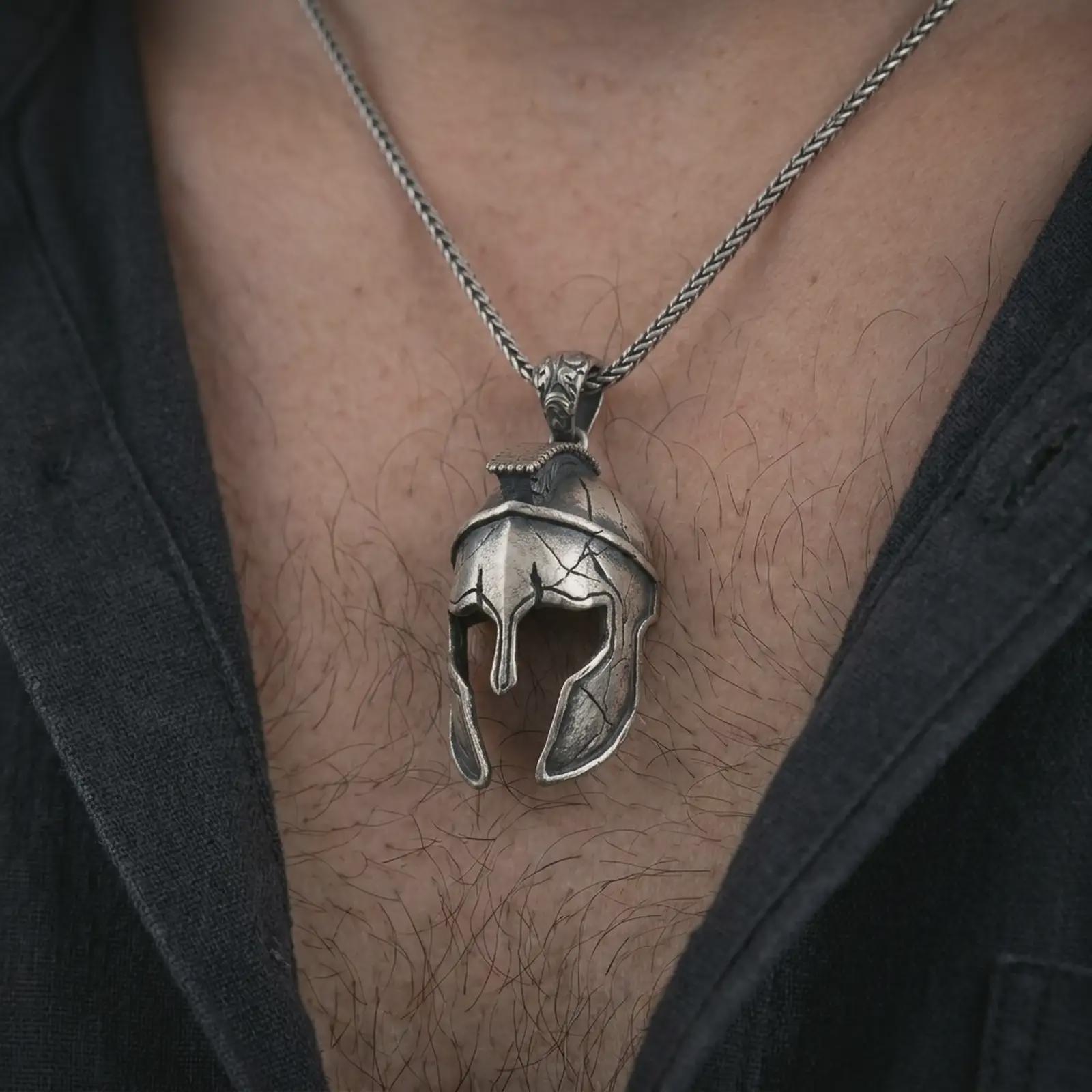 Oxidized Spartan helmet pendant necklace worn on the chest, close-up lifestyle jewelry photo showing the warrior helmet charm on a spiga chain with dark clothing.