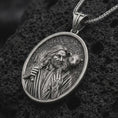 Load image into Gallery viewer, Oxidized Good Shepherd Jesus pendant necklace on textured volcanic rock, close-up studio shot highlighting the shepherd relief, lamb detail, and antique silver contrast.
