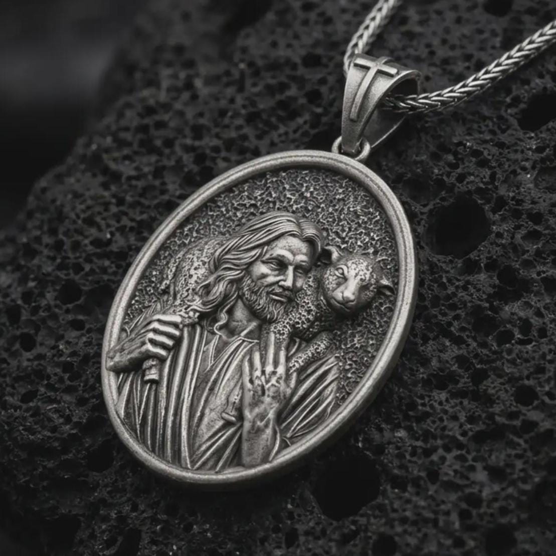 Oxidized Good Shepherd Jesus pendant necklace on textured volcanic rock, close-up studio shot highlighting the shepherd relief, lamb detail, and antique silver contrast.
