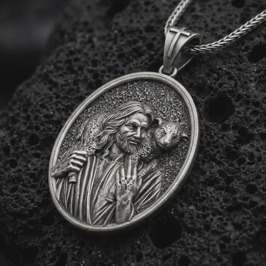 Oxidized Good Shepherd Jesus pendant necklace on textured volcanic rock, close-up studio shot highlighting the shepherd relief, lamb detail, and antique silver contrast.