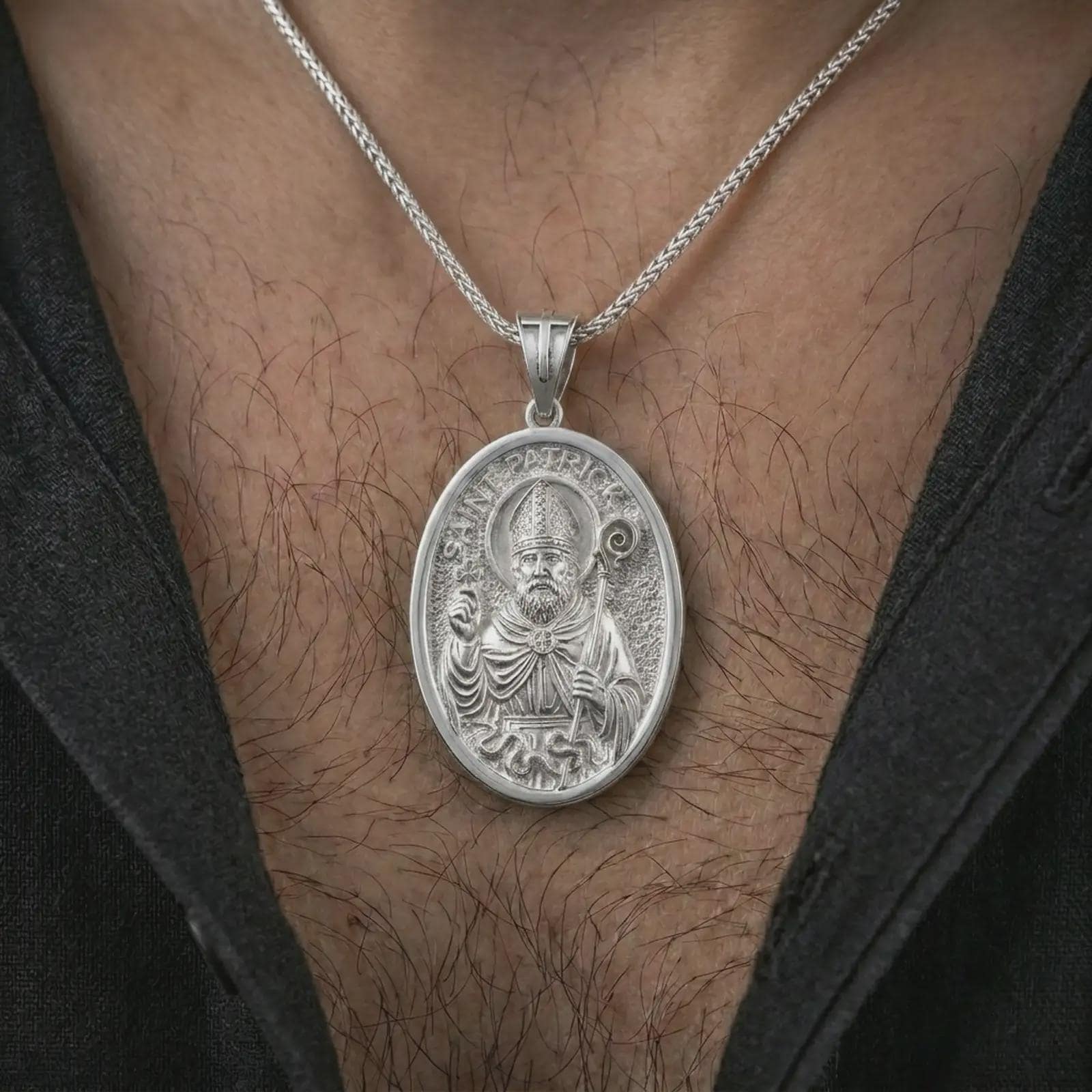 Polished silver Saint Patrick pendant necklace worn on the chest, masculine lifestyle shot highlighting the bishop relief, shamrock detail, and bright silver finish.