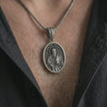 Load image into Gallery viewer, Oxidized Saint Paul pendant necklace worn on the chest, close-up lifestyle jewelry photo showing the religious medallion on a spiga chain with dark clothing.
