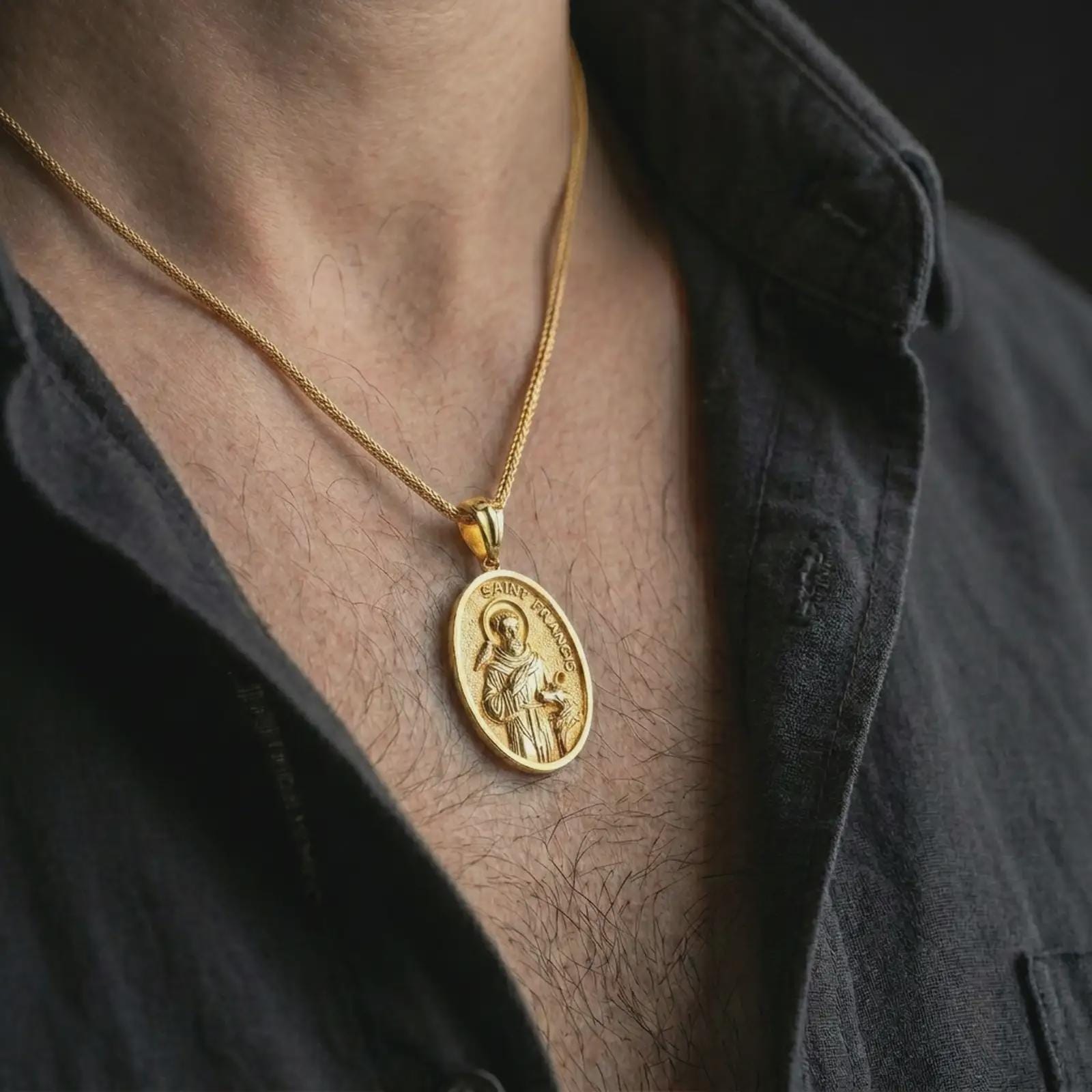 Gold plated Saint Francis pendant necklace worn on the chest, premium lifestyle jewelry photo with the Saint Francis medal centered on a spiga chain.