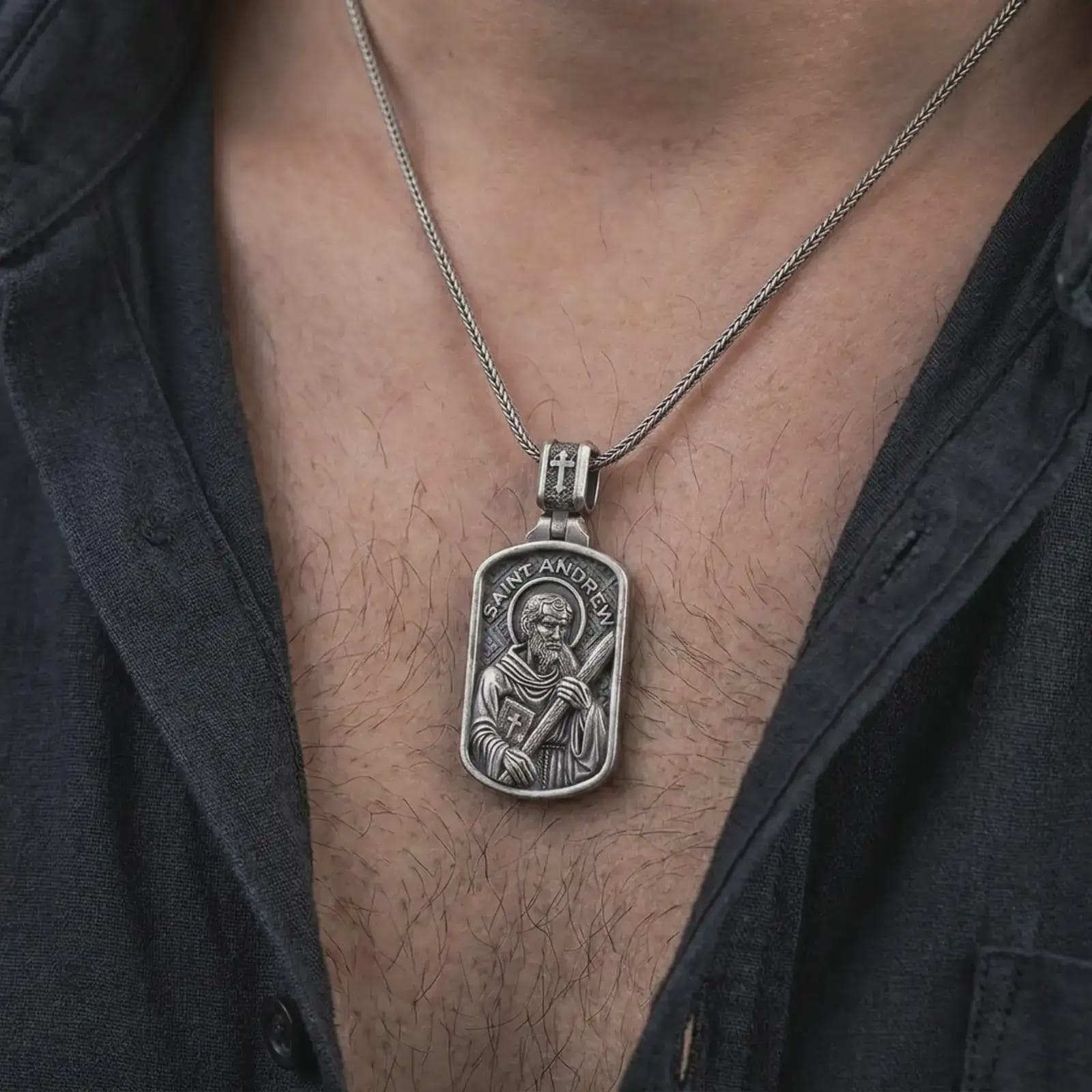 Oxidized Saint Andrew dog tag pendant necklace worn on the chest, close-up lifestyle jewelry photo showing the religious medallion on a spiga chain with dark clothing.