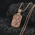 Load image into Gallery viewer, Rose gold plated Saint Andrew dog tag pendant necklace on textured volcanic rock, detailed macro product shot with soft warm reflections and devotional Saint Andrew design.
