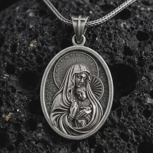 Oxidized Virgin Mary and baby Jesus pendant necklace on textured volcanic rock, close-up studio shot highlighting the mother and child relief, halo, star border, and antique silver contrast.