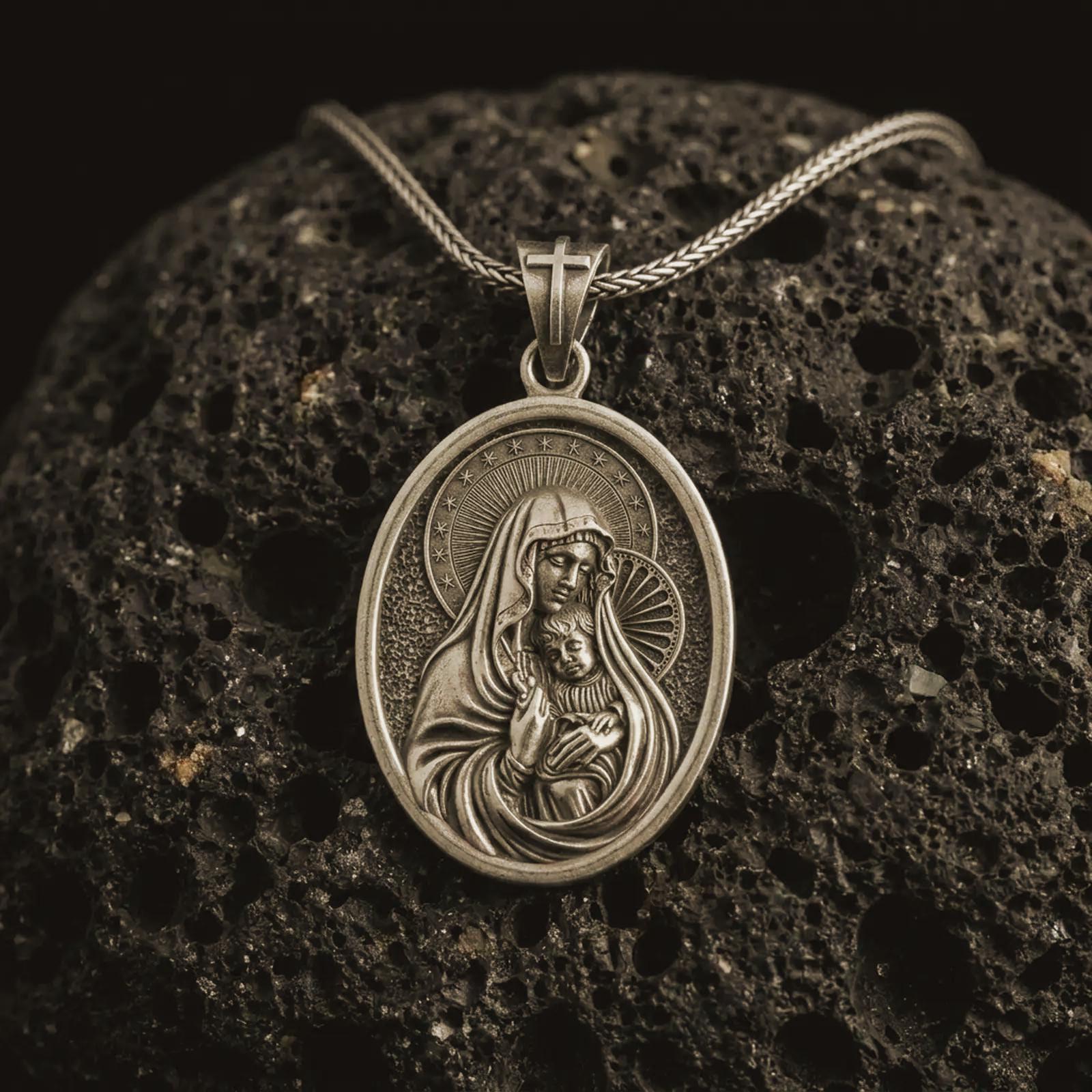 Bronze Virgin Mary and baby Jesus pendant necklace on textured volcanic rock, close-up studio shot highlighting the mother and child relief, halo, star border, and antique silver contrast.
