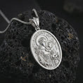 Load image into Gallery viewer, Polished silver Saint Anthony of Padua pendant necklace on textured volcanic rock, centered macro jewelry photo with detailed Catholic medal engraving and bright silver highlights.
