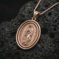 Load image into Gallery viewer, Rose gold plated Our Lady of Guadalupe spinner pendant necklace on textured volcanic rock, detailed macro product shot with soft warm reflections and devotional Marian symbolism.
