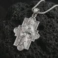 Load image into Gallery viewer, Polished silver Good Shepherd cross pendant necklace on textured volcanic rock, centered macro jewelry photo with detailed Christian icon relief and bright silver highlights.
