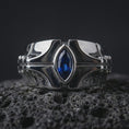 Load image into Gallery viewer, A sterling silver ring with a polished silver finish and marquise blue stone displayed on textured volcanic rock in a premium macro shot.
