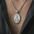 Load image into Gallery viewer, Polished silver Saint Barbara pendant necklace worn on the chest, masculine lifestyle shot highlighting the crowned saint relief, cross, tower detail, and bright silver finish.
