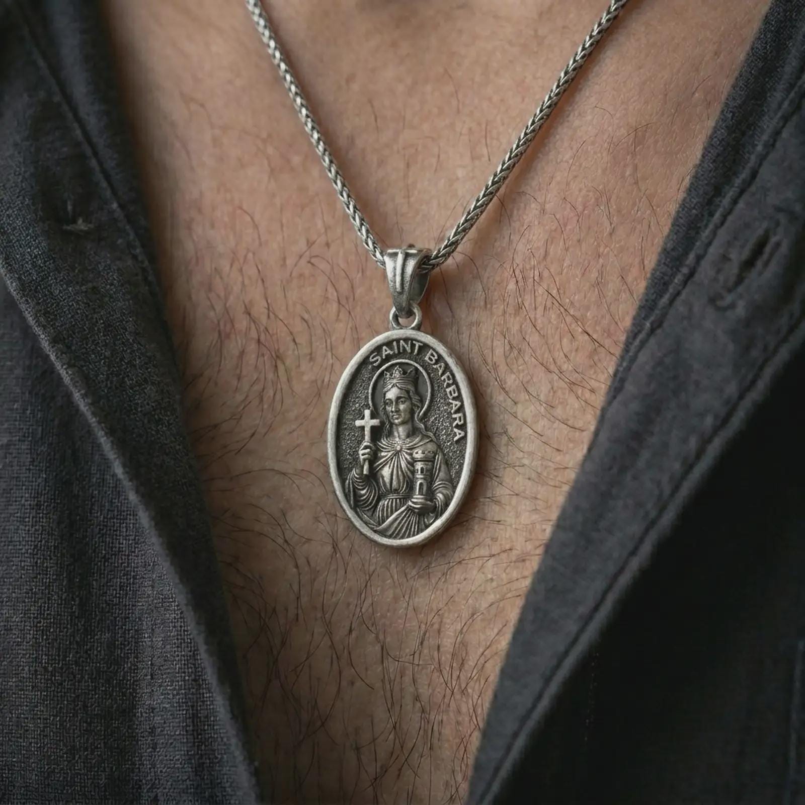 Oxidized Saint Barbara pendant necklace worn on the chest, close-up lifestyle jewelry photo showing the Catholic protection medallion on a spiga chain with dark clothing.