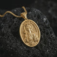 Load image into Gallery viewer, Gold plated Saint Barbara pendant necklace on textured volcanic rock, premium close-up studio composition emphasizing the crowned saint figure, cross, and tower symbolism.
