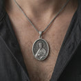 Load image into Gallery viewer, Oxidized Saint James the Apostle pendant necklace worn on the chest, close-up lifestyle jewelry photo showing the religious medallion on a spiga chain with dark clothing.
