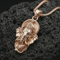 Load image into Gallery viewer, Rose gold plated Ganesha pendant necklace on textured volcanic rock, detailed macro product shot with soft warm reflections and sacred elephant deity design.

