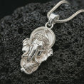 Load image into Gallery viewer, Polished silver Ganesha pendant necklace on textured volcanic rock, centered macro jewelry photo with detailed Hindu deity relief and bright silver highlights.
