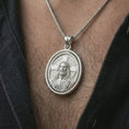 Load image into Gallery viewer, Polished silver spinning Jesus Christ pendant necklace worn on the chest, masculine lifestyle shot highlighting the Jesus portrait, cross halo detail, and bright silver finish.
