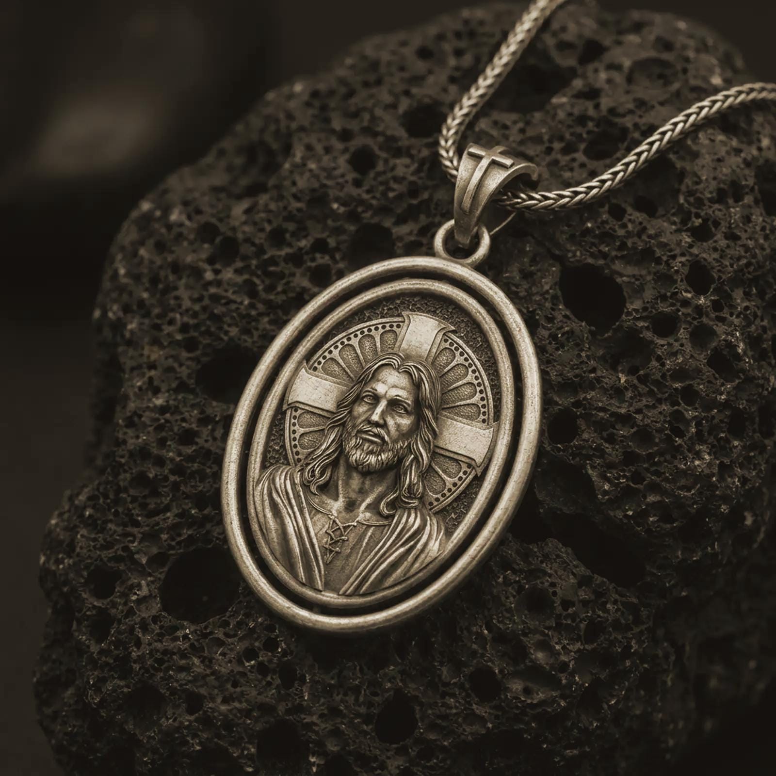 Bronze spinning Jesus Christ pendant necklace on textured volcanic rock, close-up studio shot highlighting the Jesus portrait, cross halo, oval frame, and antique silver contrast.