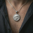 Load image into Gallery viewer, A polished silver Eye of Horus pendant is worn on the neck in a premium close-up lifestyle image, showing the ancient eye motif clearly.
