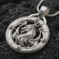 Load image into Gallery viewer, A polished silver dragon pendant is displayed on black volcanic rock in a premium macro studio close-up with sharp fantasy-inspired texture.
