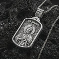 Load image into Gallery viewer, Polished silver Saint Jude dog tag pendant necklace on textured volcanic rock, centered macro jewelry photo with detailed Christian medal engraving and bright silver highlights.
