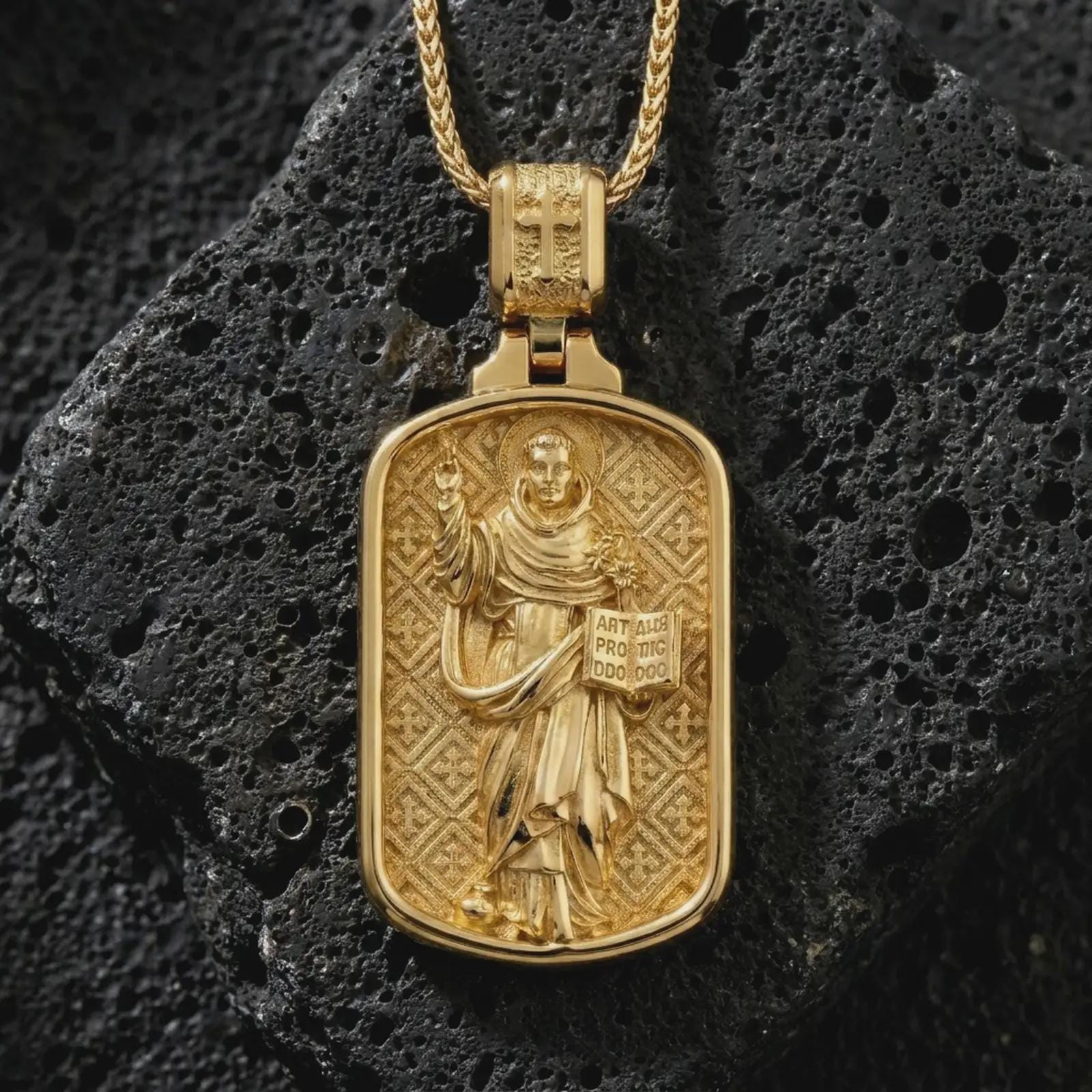 Gold plated Saint Dominic dog tag pendant necklace on textured volcanic rock, premium close-up studio composition emphasizing the saint figure, sacred book, and lily symbolism.