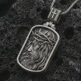 Load image into Gallery viewer, Oxidized crucified Jesus dog tag pendant necklace on textured volcanic rock, close-up studio shot highlighting the side-profile Christ relief, crown of thorns, flowing hair, and antique silver contrast.
