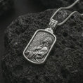 Load image into Gallery viewer, Polished silver Jesus prayer dog tag pendant necklace on textured volcanic rock, centered macro jewelry photo with detailed Christian relief and bright silver highlights.

