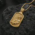 Load image into Gallery viewer, Gold plated Jesus prayer dog tag pendant necklace on textured volcanic rock, premium close-up studio composition emphasizing the praying Jesus figure, halo, and rectangular medallion design.
