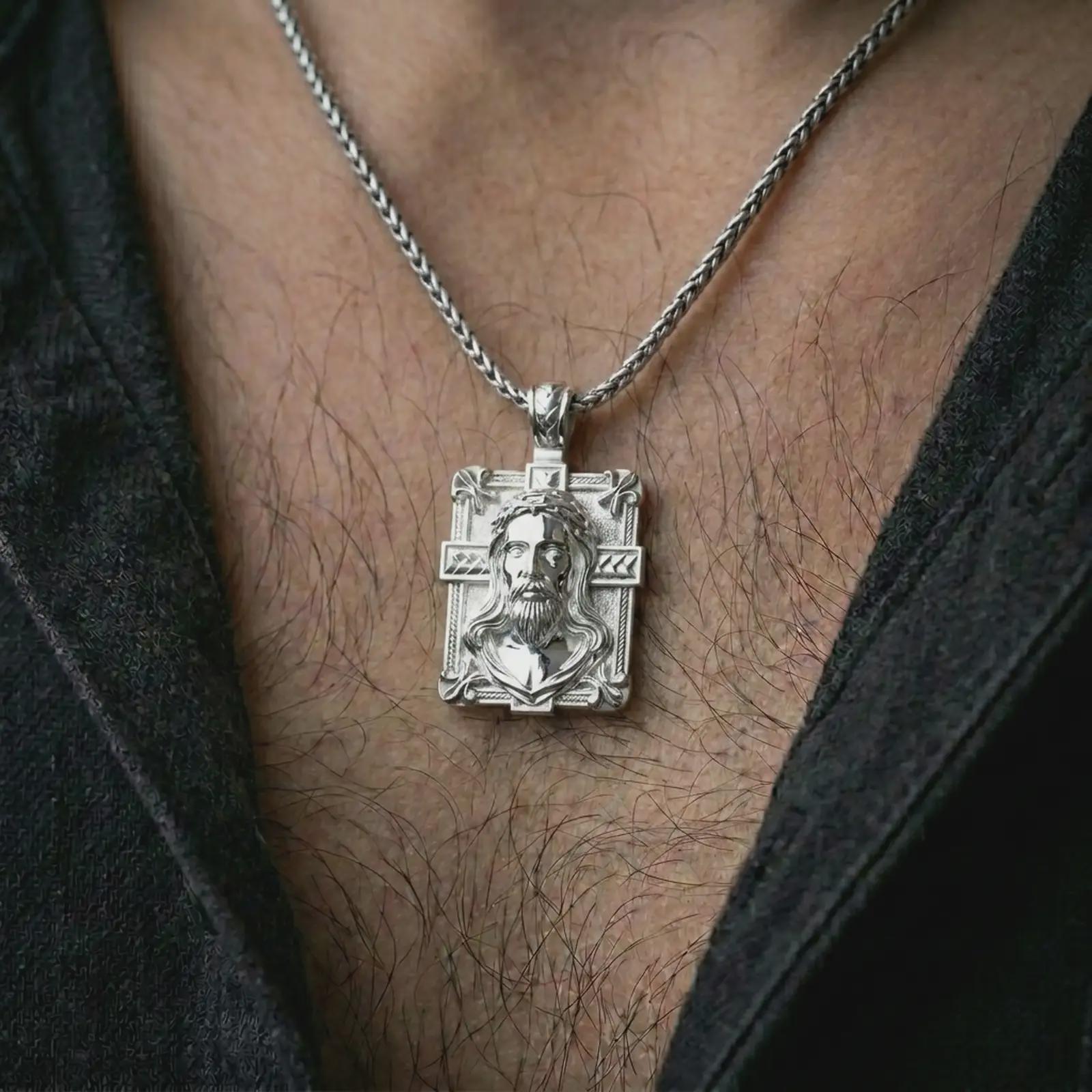 A Jesus crucifix pendant in a polished silver finish worn on the neck on a chain in a clean lifestyle close-up.