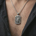 Load image into Gallery viewer, A polished silver Hannya mask pendant is worn on the neck in a premium close-up lifestyle image, showing the detailed demon mask motif clearly.
