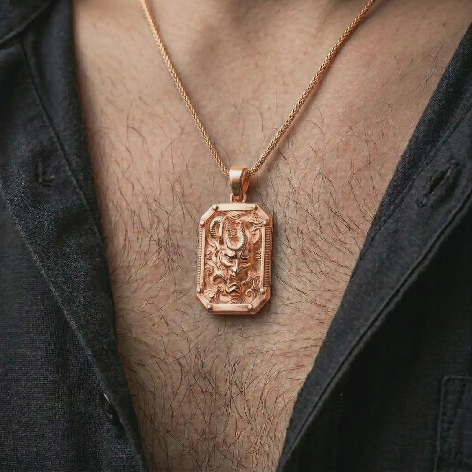 A rose gold plated Hannya mask pendant is worn on the neck in a close-up lifestyle composition, highlighting its horned mask design and ornate frame.