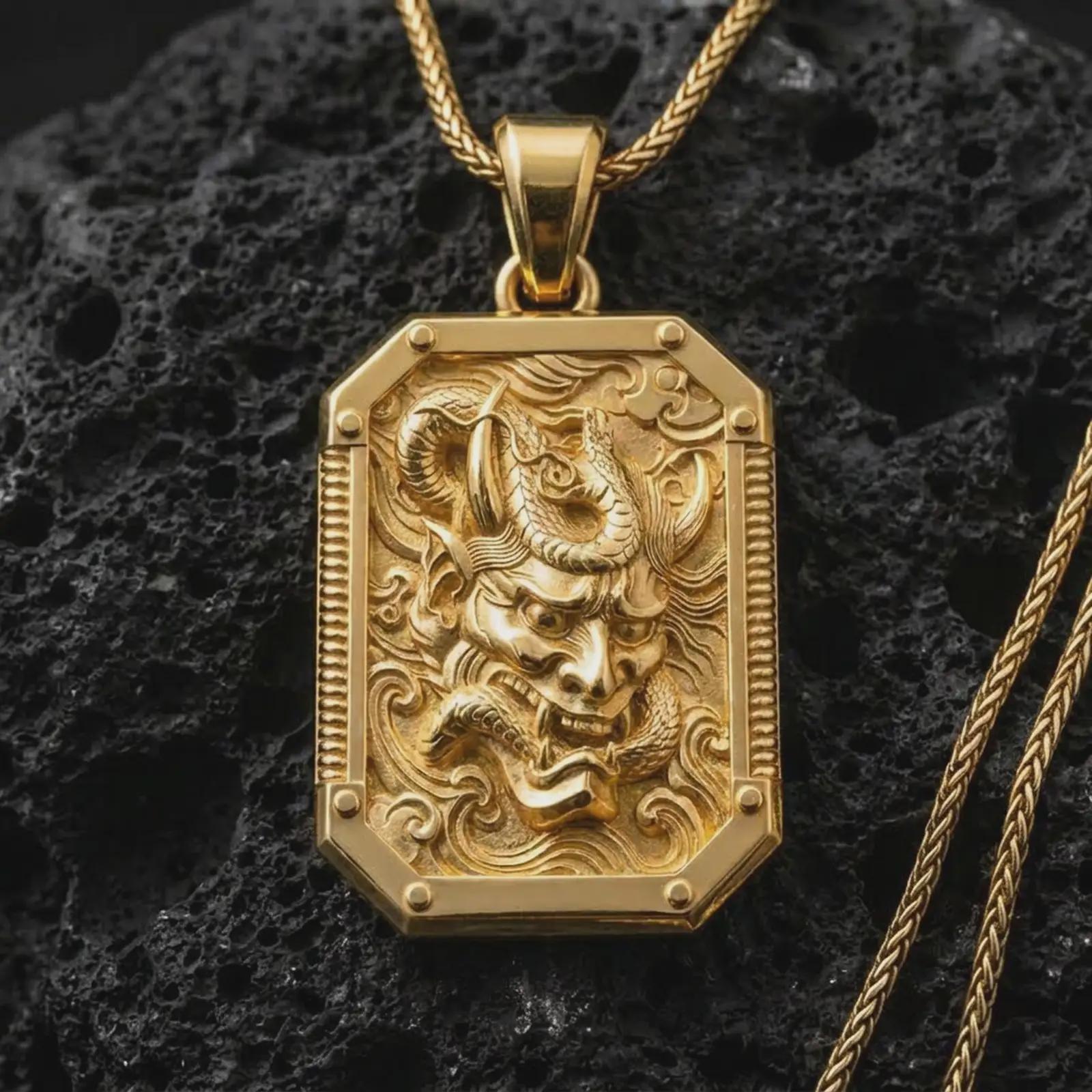 A gold plated Hannya mask pendant lies on textured volcanic rock in a dramatic studio macro shot, highlighting the Japanese protection amulet design.
