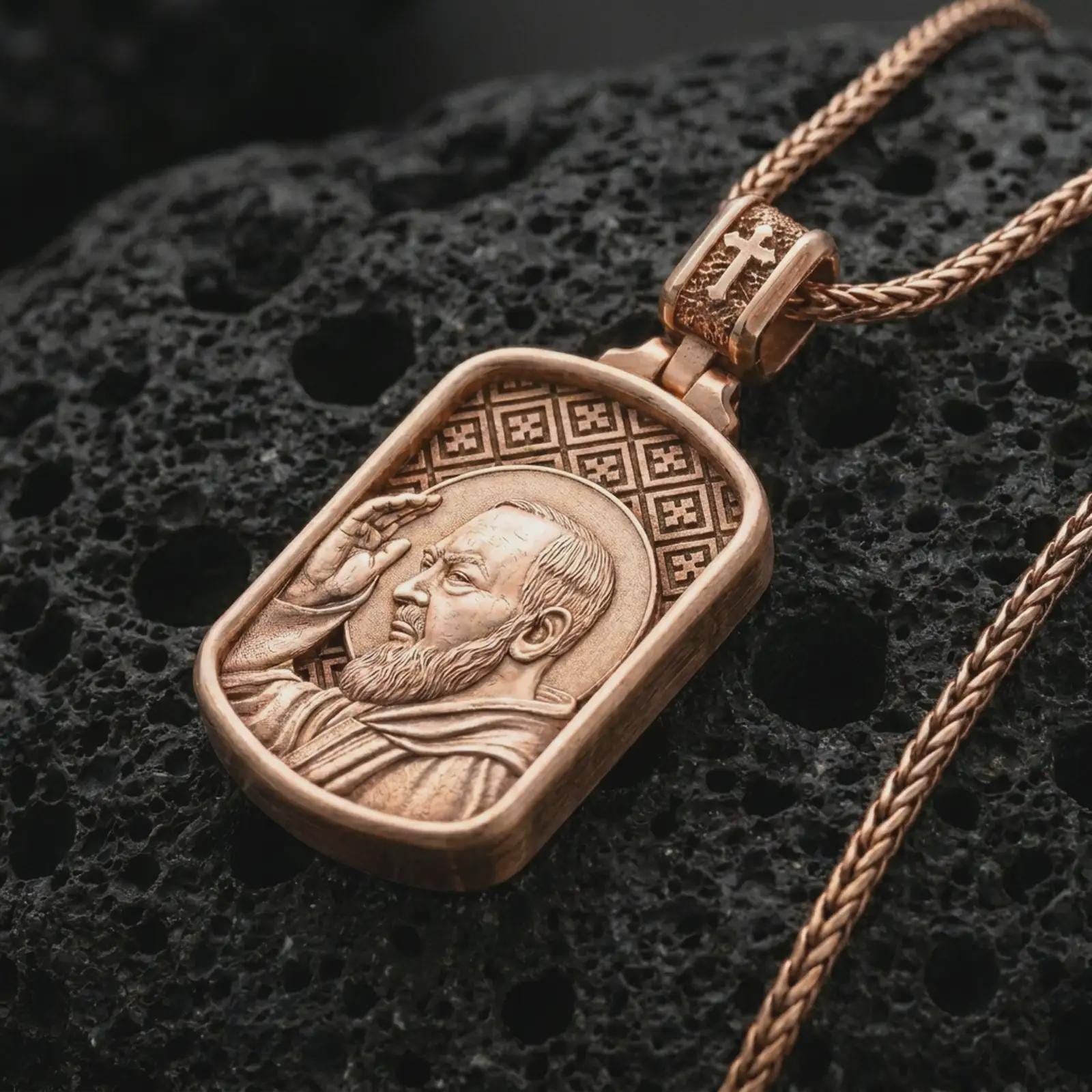 Rose gold plated Saint Padre Pio dog tag pendant necklace on textured volcanic rock, detailed macro product shot with soft warm reflections and devotional saint symbolism.