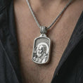 Load image into Gallery viewer, Polished silver Saint Padre Pio dog tag pendant necklace worn on the chest, masculine lifestyle shot highlighting the saint profile relief, blessing gesture, and bright silver finish.
