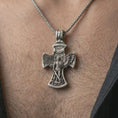 Load image into Gallery viewer, Oxidized Saint Michael cross pendant necklace worn on the chest, close-up lifestyle jewelry photo showing the religious archangel pendant on a spiga chain with dark clothing.
