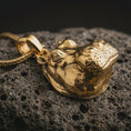 Load image into Gallery viewer, Gold plated hippo head pendant necklace on textured volcanic rock, premium close-up studio composition emphasizing the realistic hippopotamus face, ears, and dimensional form.
