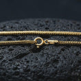 Load image into Gallery viewer, Gold plated Italian foxtail chain necklace on textured volcanic rock, premium close-up studio composition emphasizing the woven links, clasp detail, and refined chain craftsmanship.
