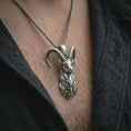 Load image into Gallery viewer, Polished silver ram horn pendant necklace worn on the chest, masculine lifestyle shot highlighting the sculpted ram head, curved horns, and bright silver finish.
