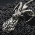 Load image into Gallery viewer, Oxidized ram horn pendant necklace on textured volcanic rock, close-up studio shot highlighting the sculpted goat head, curved horns, leaf-like beard detail, and antique silver contrast.
